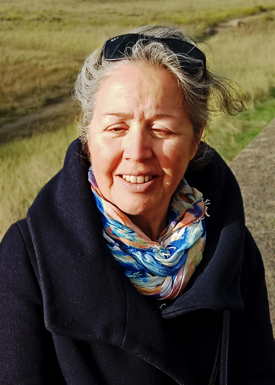 Portrait de Daniela Diaz, kinésithérapeute souriante, portant une blouse blanche, debout dans un cabinet moderne, spécialisée dans la gestion des douleurs chroniques et l'éducation somatique.